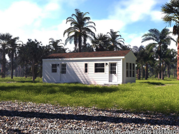 A white single-story manufactured home sits on a grassy lot surrounded by palm trees, with a gravel area in the foreground.