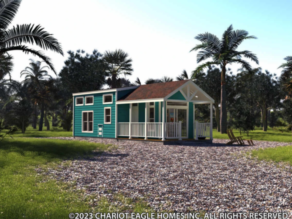 Teal tiny house with a front porch and white trim sits on a gravel lot, surrounded by palm trees and grass under a clear blue sky.