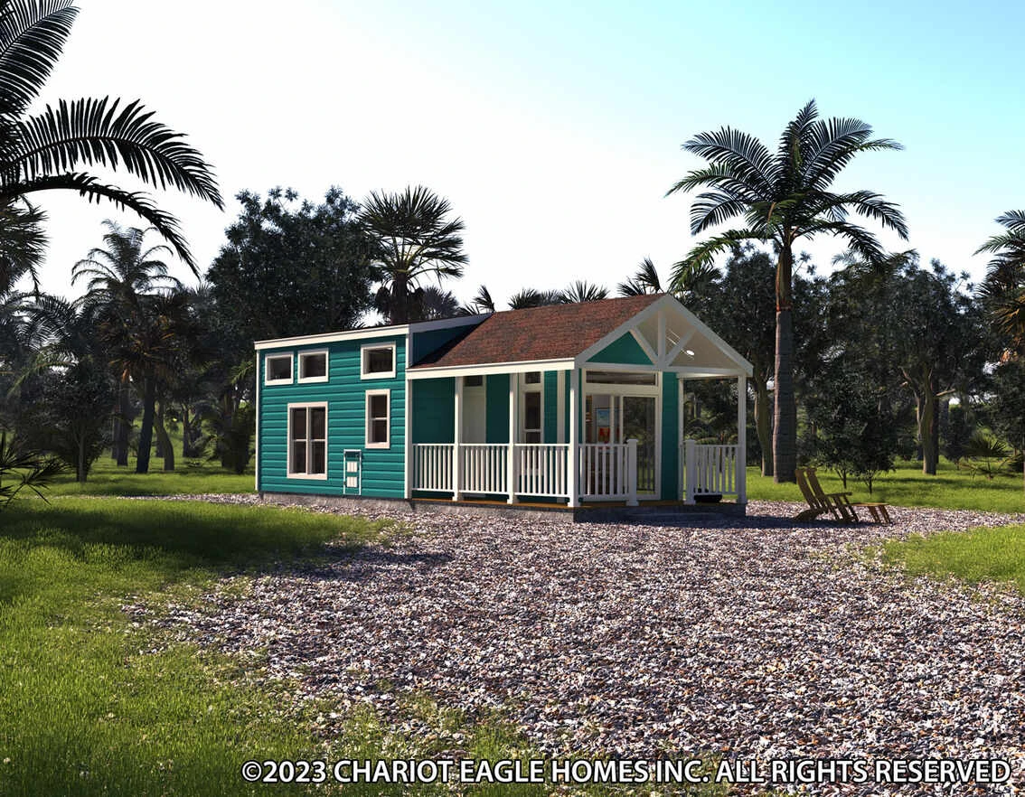 Teal tiny house with a front porch and white trim sits on a gravel lot, surrounded by palm trees and grass under a clear blue sky.