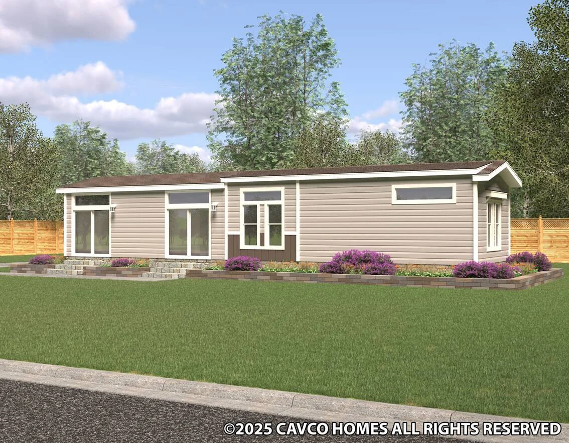 Single-story modern manufactured home with tan siding, large windows, a small front garden, and a wooden fence in the background.