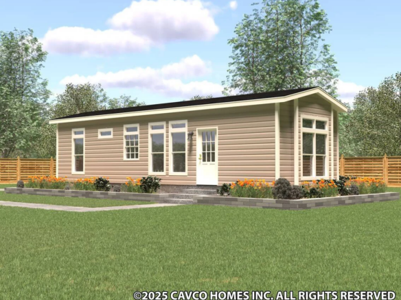 A single-story modern tiny home with tan siding, large windows, and a landscaped yard, surrounded by a wooden fence and trees under a partly cloudy sky.
