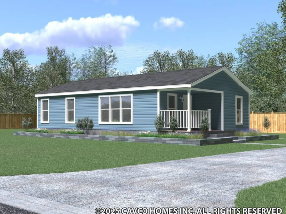 Single-story blue manufactured home with white trim, a small covered porch, and landscaped yard, set on a green lawn with trees and a wooden fence in the background.