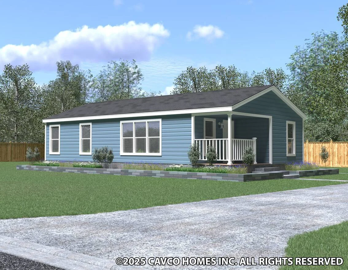 Single-story blue manufactured home with white trim, a small covered porch, and landscaped yard, set on a green lawn with trees and a wooden fence in the background.