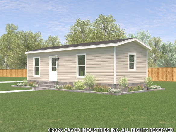 Small beige manufactured home with white trim, a gable roof, and a white door, set on a grassy lawn with flower beds and trees in the background.