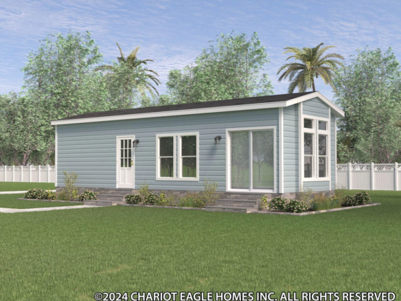 A small, light blue manufactured home with large windows, a white door, and a gabled roof sits on a grassy lawn with landscaping and trees in the background.