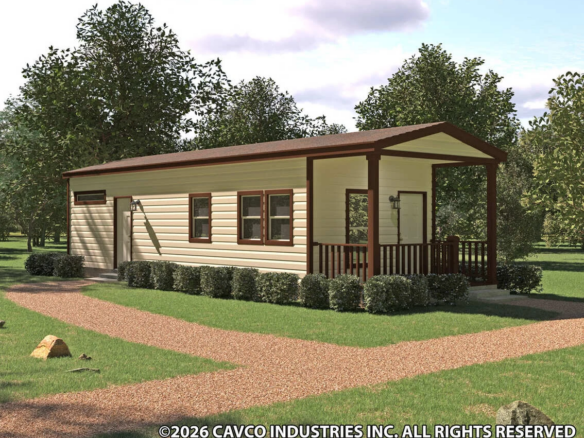 A single-story manufactured home with a covered porch, cream siding, and brown trim, surrounded by trees and grass, with a gravel walkway in front.