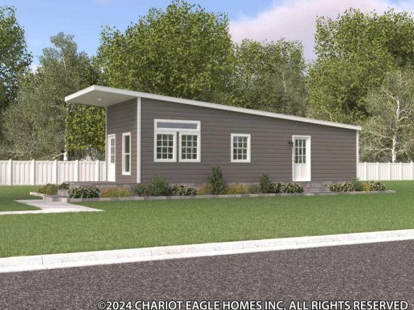 A modern, single-story gray home with a slanted roof sits on a green lawn, surrounded by trees and a white fence.