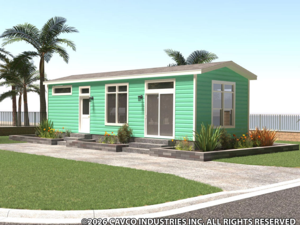 A modern, single-story green modular home with large windows, surrounded by landscaped plants and palm trees.