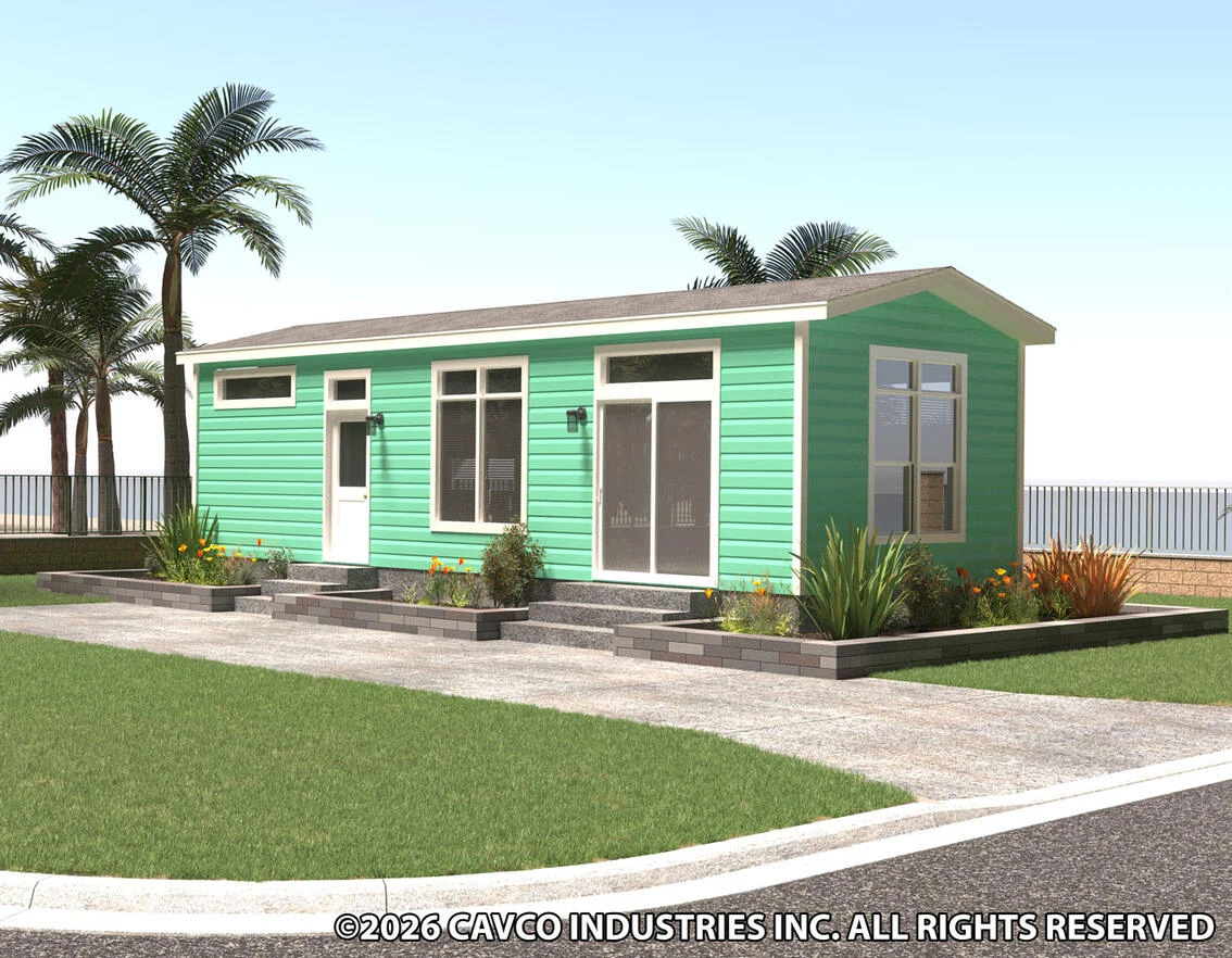 A modern, single-story green modular home with large windows, surrounded by landscaped plants and palm trees.