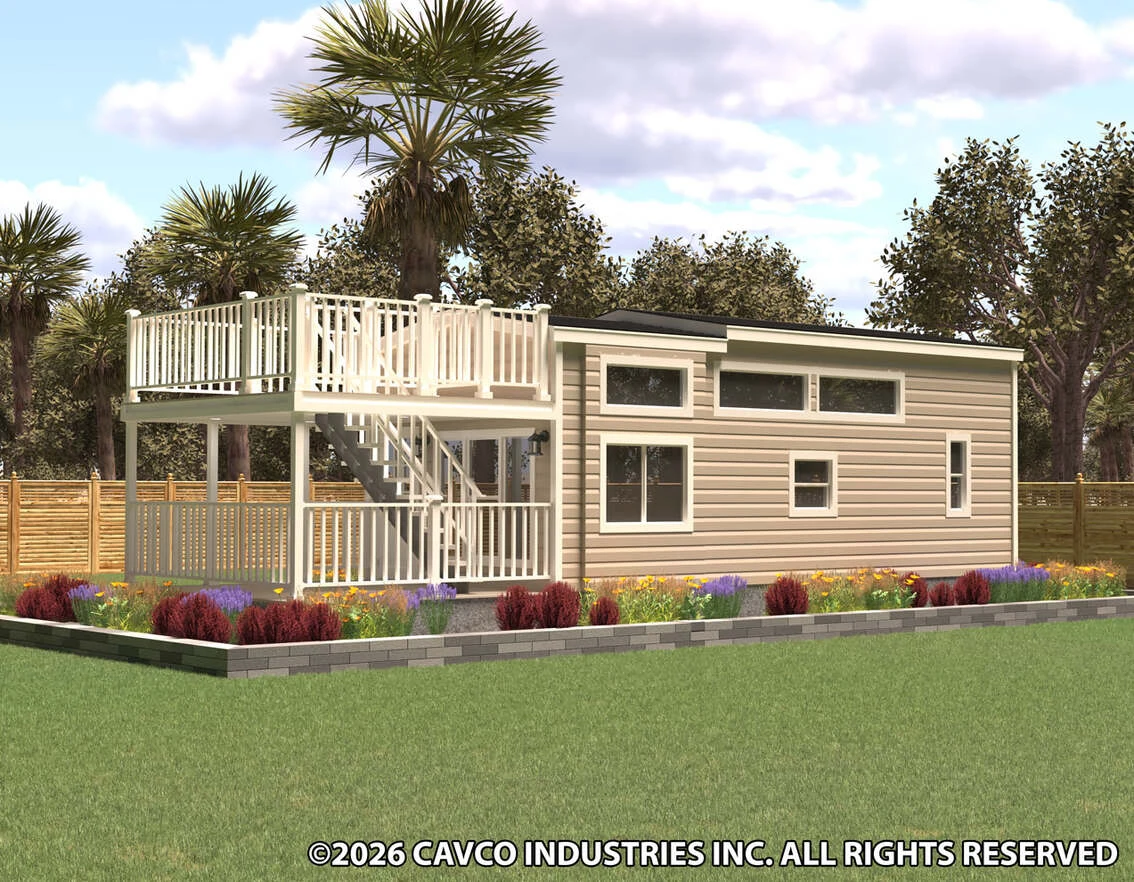 A small modern house with horizontal siding, large windows, an upper deck with white railing, and a staircase, surrounded by landscaped gardens and trees.