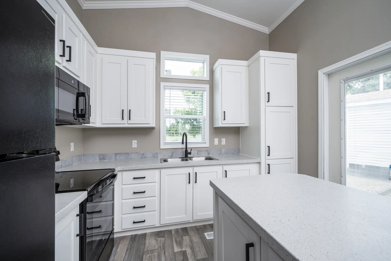 Modern kitchen with white cabinets, black appliances, a center island, and a window above the sink letting in natural light.
