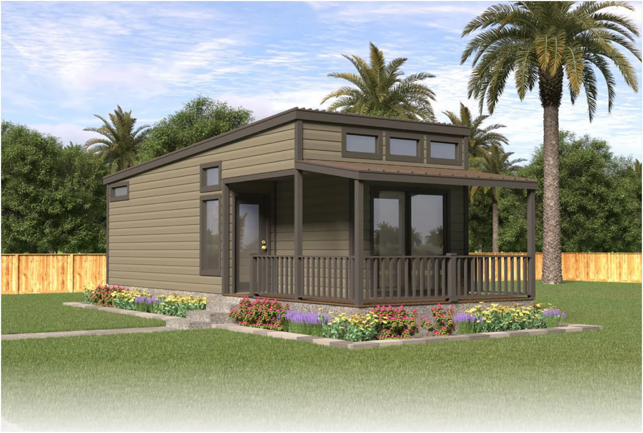 A small modern house with a covered front porch sits in a landscaped yard with flowers, grass, palm trees, and a wooden fence in the background.