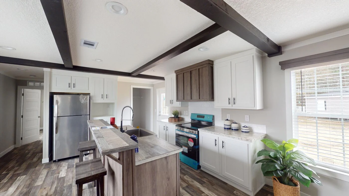 Modern kitchen with white cabinets, dark wood beams, stainless steel appliances, a central island, and a potted plant near a window with blinds.