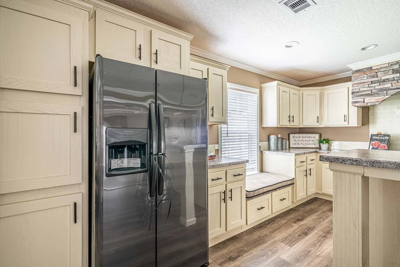 Modern kitchen with cream-colored cabinets, a stainless steel side-by-side refrigerator, wood-style flooring, and a window bench seat.