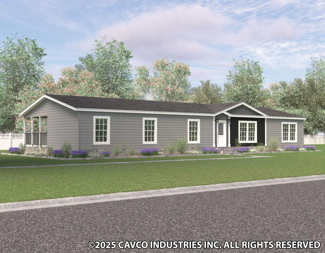 Single-story gray manufactured home with white trim, black shingle roof, front porch, multiple windows, and a lawn, surrounded by trees under a partly cloudy sky.