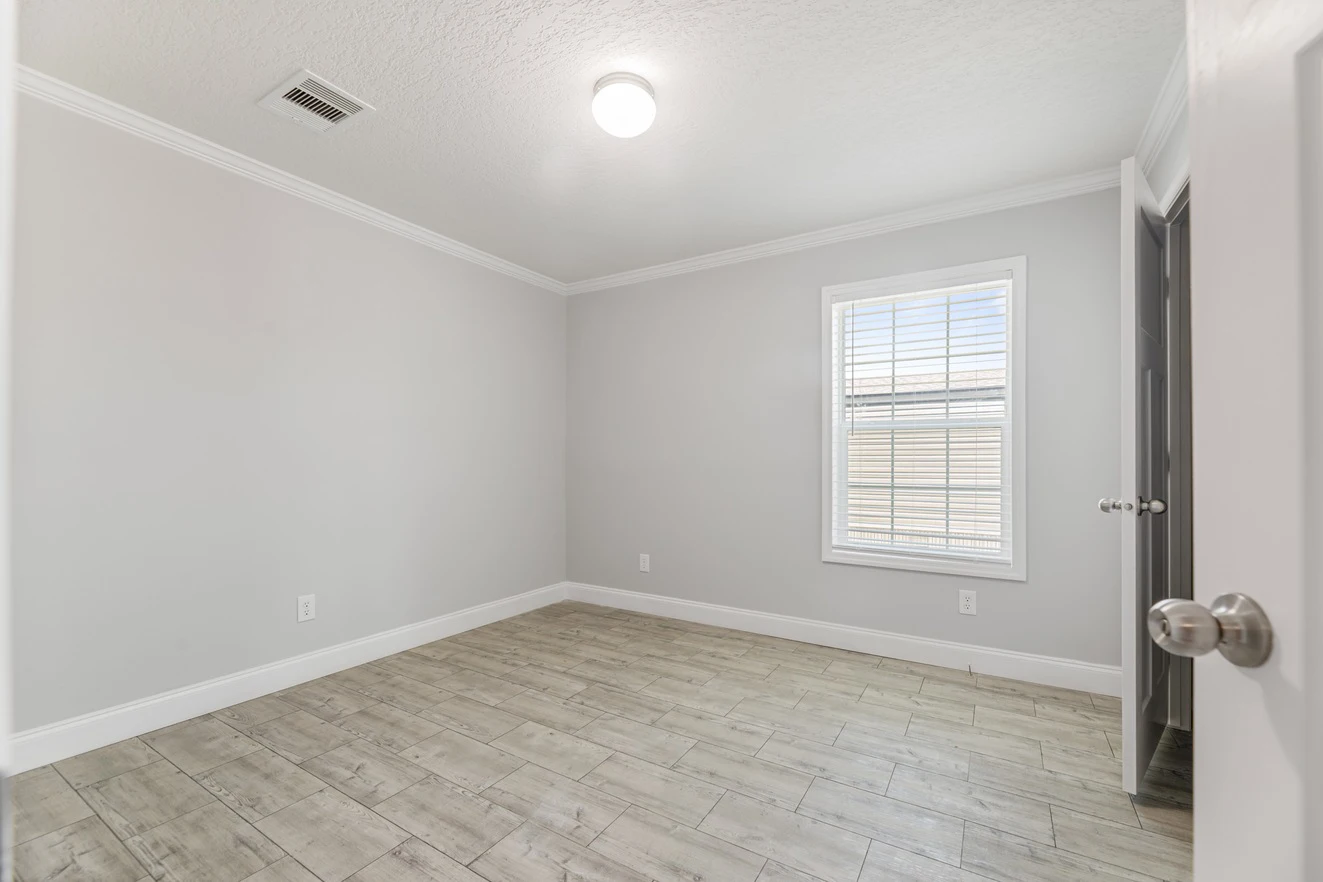 Empty room with light gray walls, tile flooring, a white ceiling, a window with blinds, overhead light, and open door.