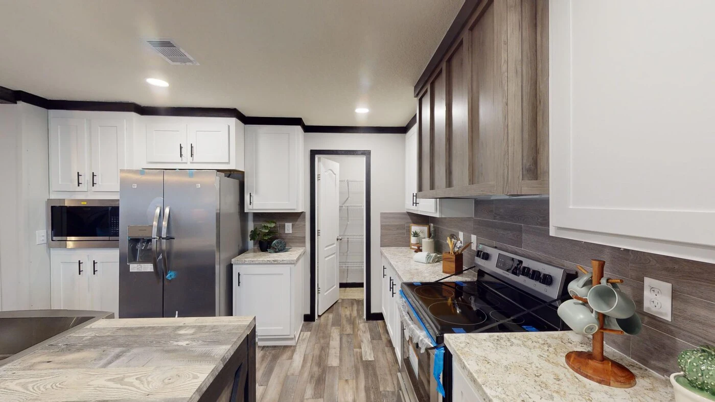 Modern kitchen with white cabinets, stainless steel appliances, wood accents, marble countertops, and a doorway leading to another room.