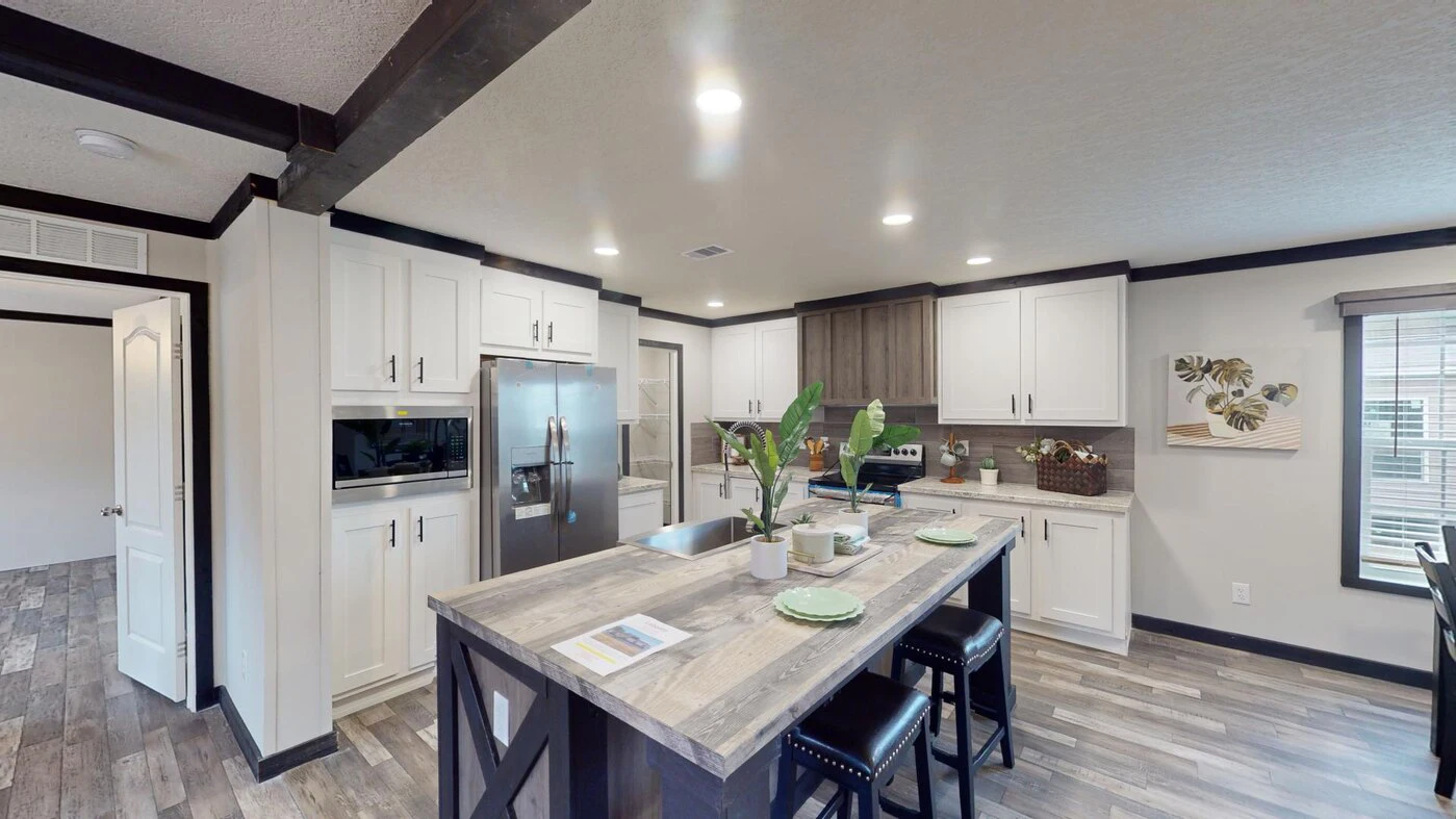 Modern kitchen with an island, stainless steel appliances, white cabinets, wood-style flooring, and barstools, viewed from the center of the room.