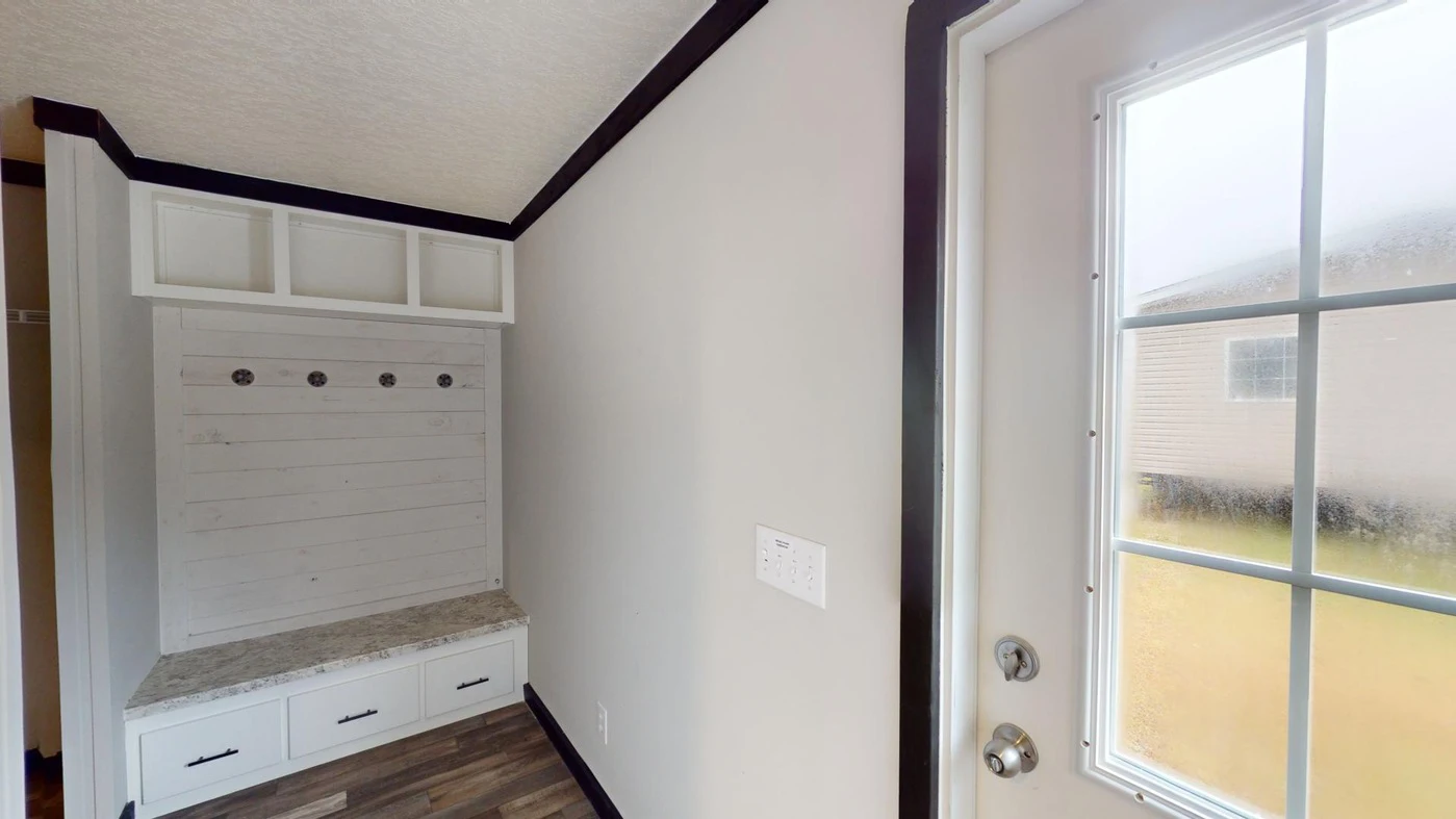 A small entryway with a white door, a wall-mounted coat rack with hooks, cabinets above and drawers below, and wood-patterned flooring.