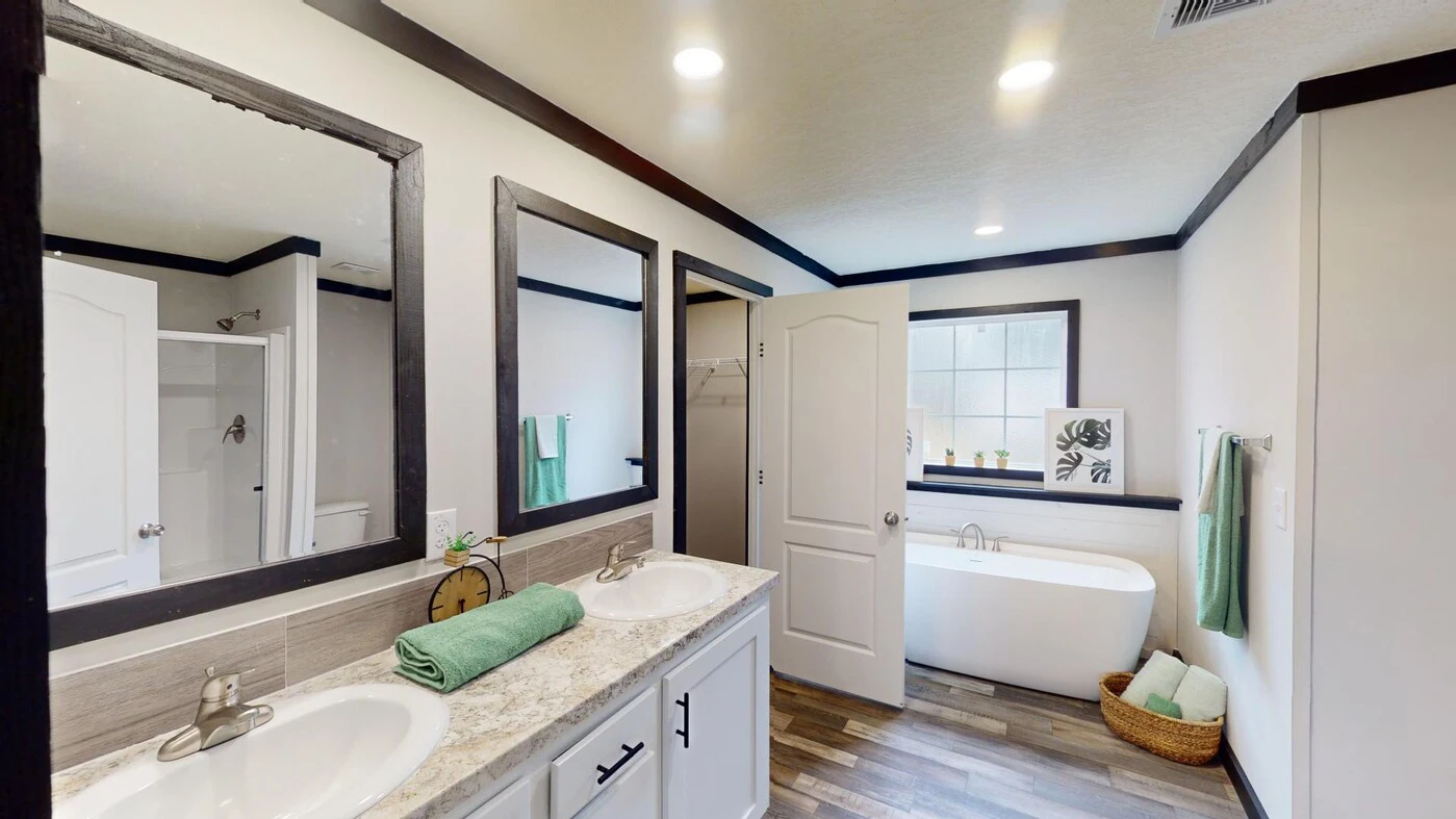 Modern bathroom with double sinks, large mirrors, a freestanding bathtub, towel racks, wood-look flooring, and recessed ceiling lights.