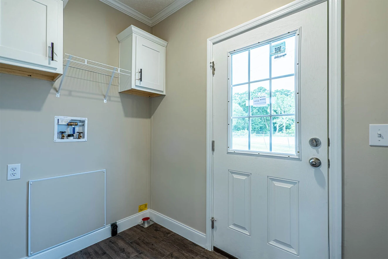 Laundry room with a white door, upper cabinets, a wire shelf, washer and dryer hookups, and wood-look flooring.