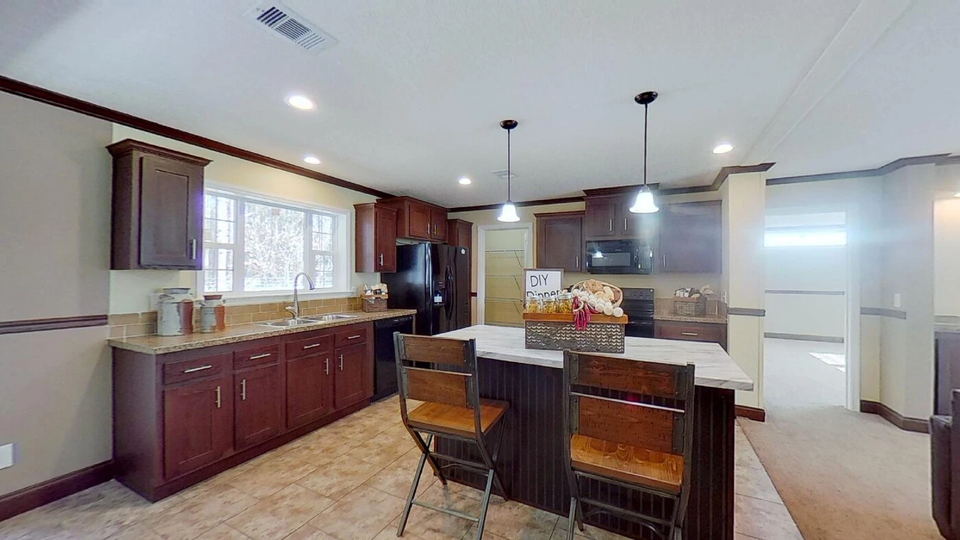 Modern kitchen with dark wood cabinets, a large island with two chairs, pendant lights, and stainless steel appliances. A basket labeled "DIY Snacks" sits on the island.