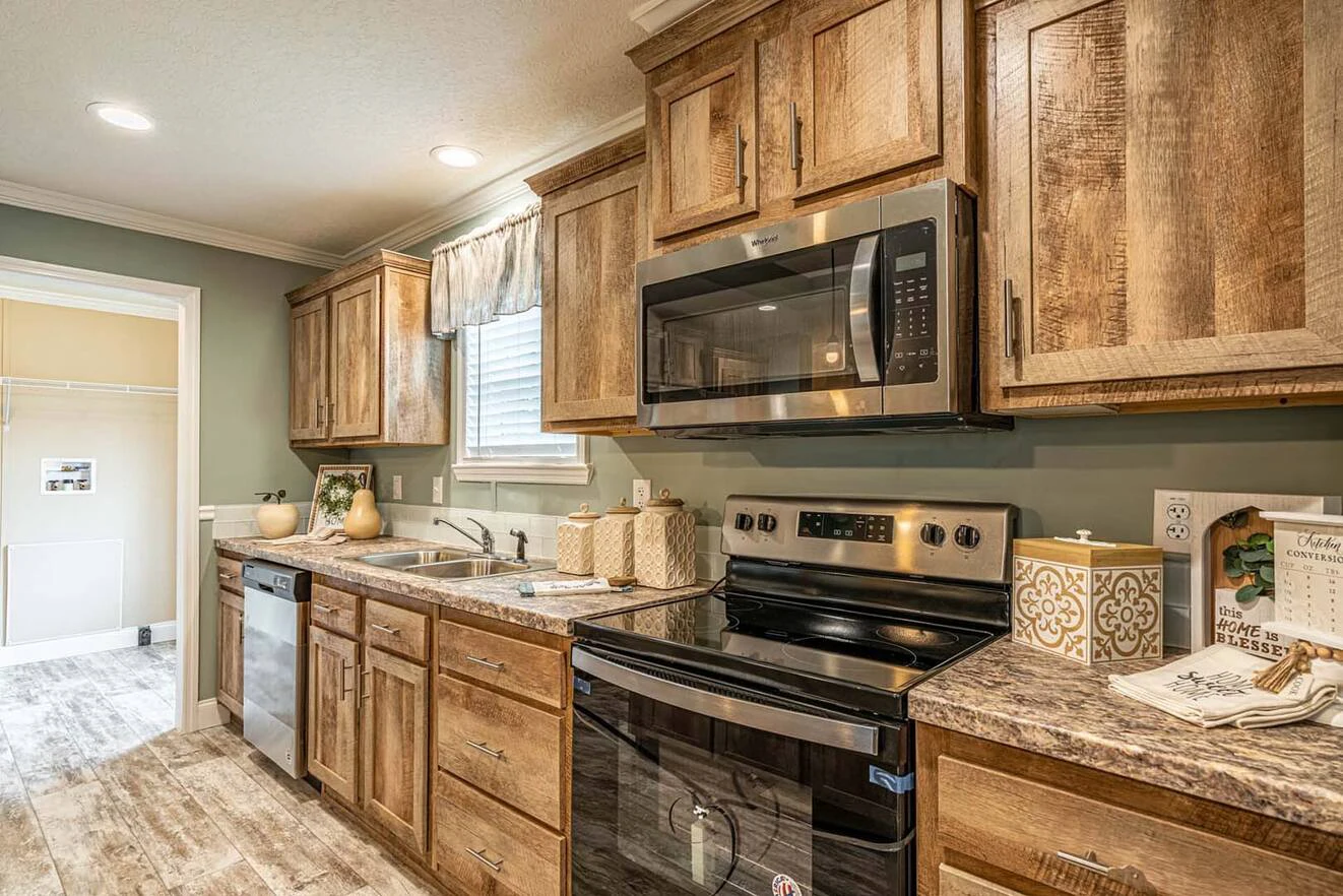 Modern kitchen with wooden cabinets, stainless steel appliances, a double sink, marble-patterned countertops, and green walls under ceiling lighting.