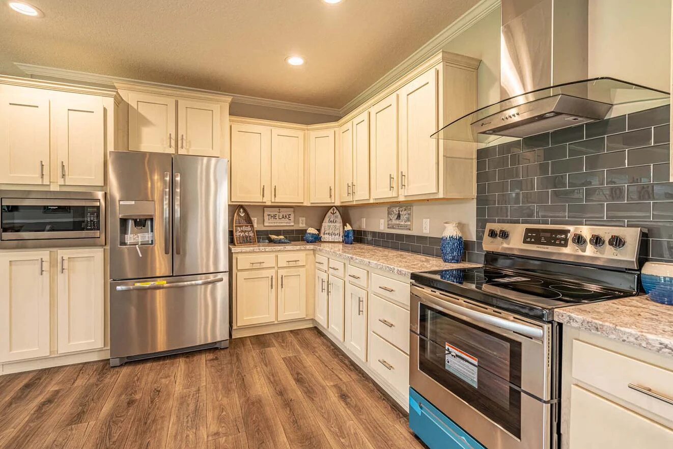 Modern kitchen with stainless steel appliances, white cabinets, gray subway tile backsplash, marble countertops, and wood-style flooring.