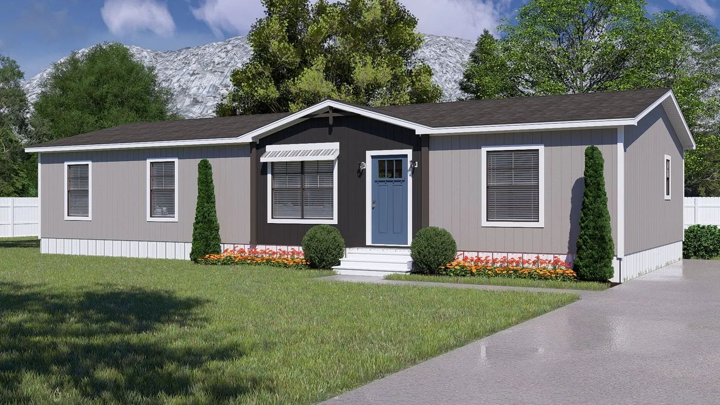 A gray, single-story manufactured home with a blue front door, small front porch, two shrubs, and flower beds, set on a lawn with trees and a mountain in the background.