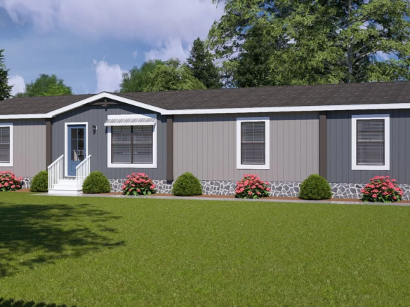 A single-story manufactured home with gray siding, white trim, a small front porch, and a well-kept lawn with bushes and pink flowers in front.
