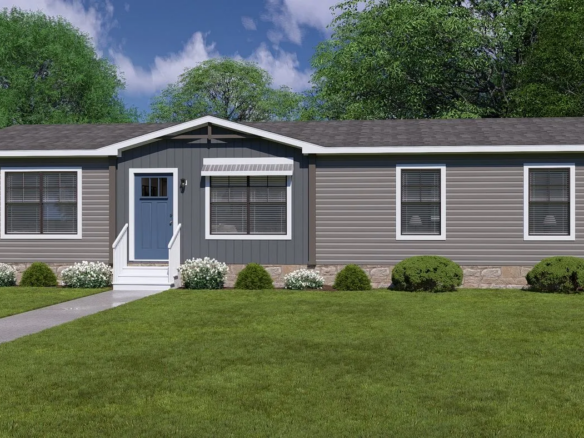 Single-story manufactured home with gray siding, a central front door, white trim, three front windows, small awning, shrub landscaping, and a lawn with a sidewalk leading to the entrance.