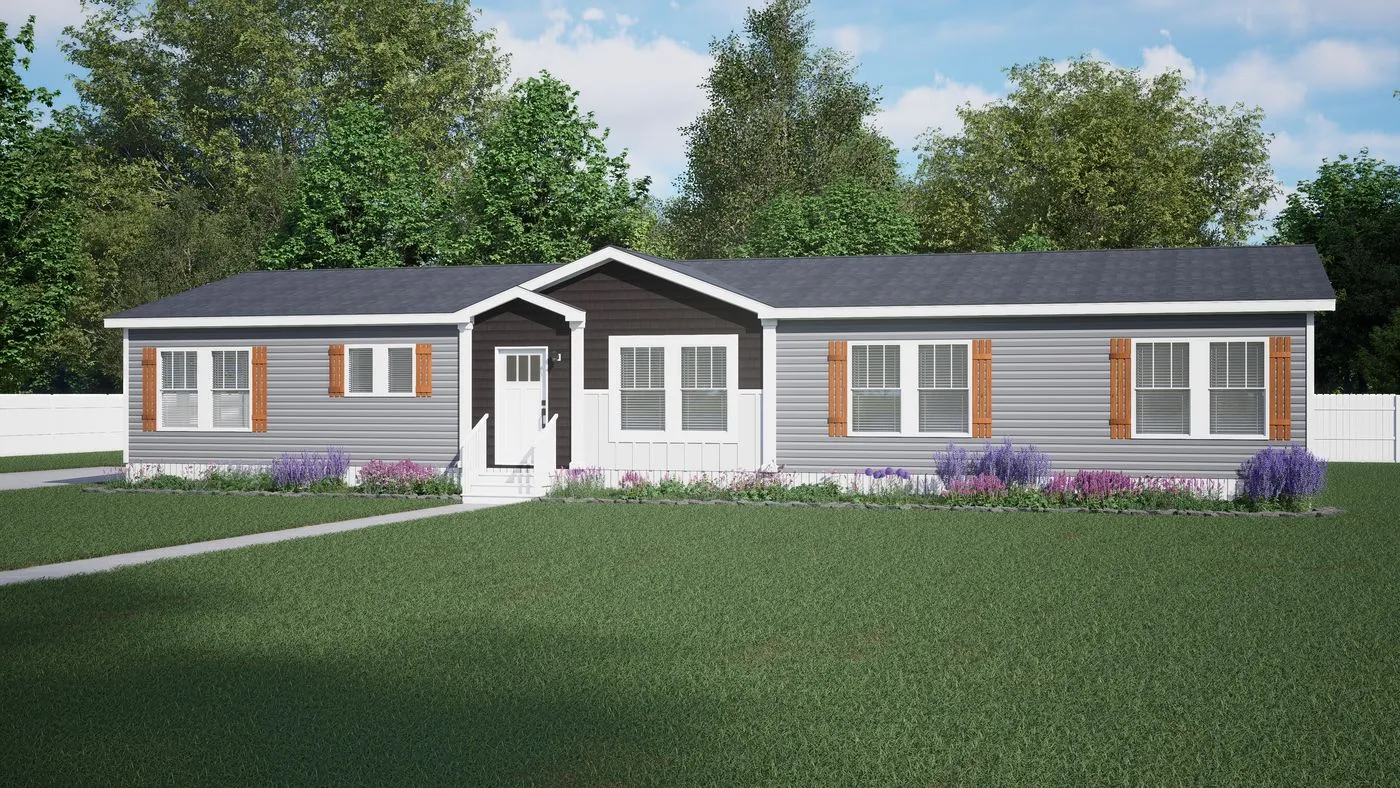 A single-story gray manufactured home with white trim, brown shutters, a small front porch, and landscaping in front, set on a grassy lawn with trees and a white fence in the background.